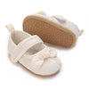 A pair of soft non-slip baby first walker shoes in cream color with a textured sole.