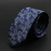 Corbata azul oscuro con diseño floral blanco, enrollada.