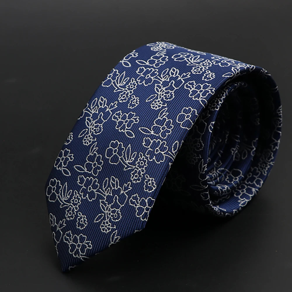 Corbata azul oscuro con diseño floral blanco, enrollada.