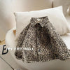 A black and beige leopard print denim shirt worn casually on a white sofa.