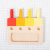 A wooden color matching puzzle featuring five colored pegs and a blank slot for matching.