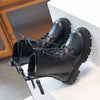 A pair of black faux leather motorcycle boots with double zippers resting on a white surface.