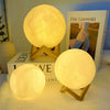 Three glowing moon-shaped LED night lights resting on a surface next to a book.