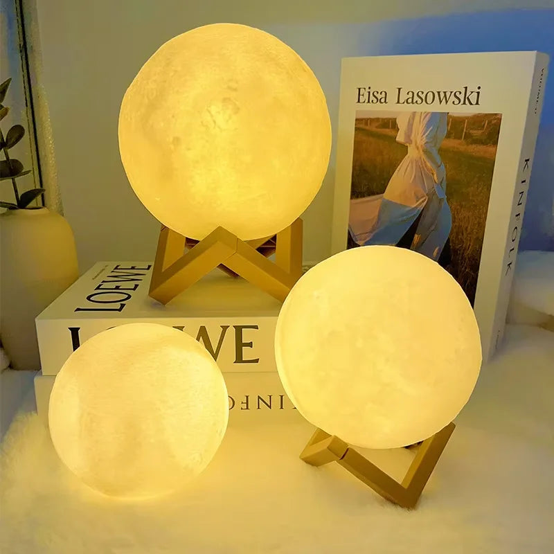 Three glowing moon-shaped LED night lights resting on a surface next to a book.