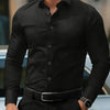 A man wearing a black long-sleeve formal shirt and dark trousers, standing outdoors.