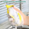 A hand is squeezing a yellow double-sided non-stick dish sponge covered in thick white foam for quick cleaning.