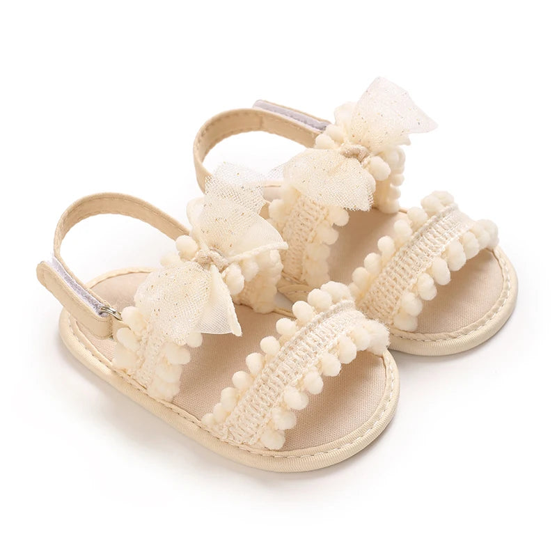 Pair of beige baby girls summer sandals with white bow embellishments