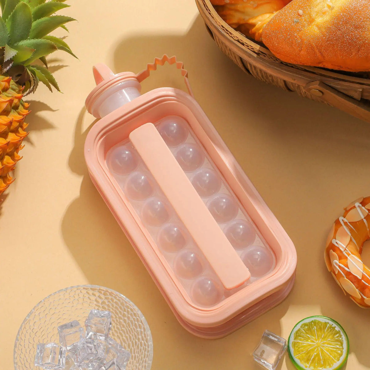 A pink portable ice cube tray with a mold for a water bottle is shown next to ice cubes and a lime slice.