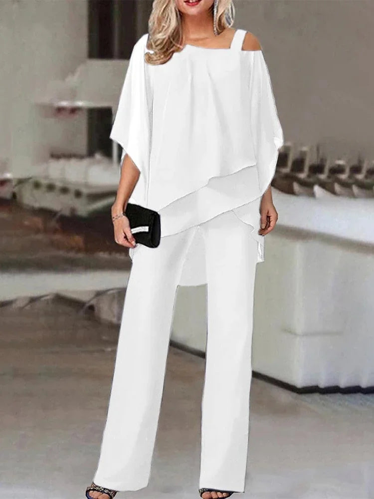 En kvinne modellerer et hvitt todelt antrekk bestående av en off-shoulder topp og vide bukser.