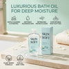 En flaske Skin So Soft badeolie og æske på en træoverflade med spa-elementer.