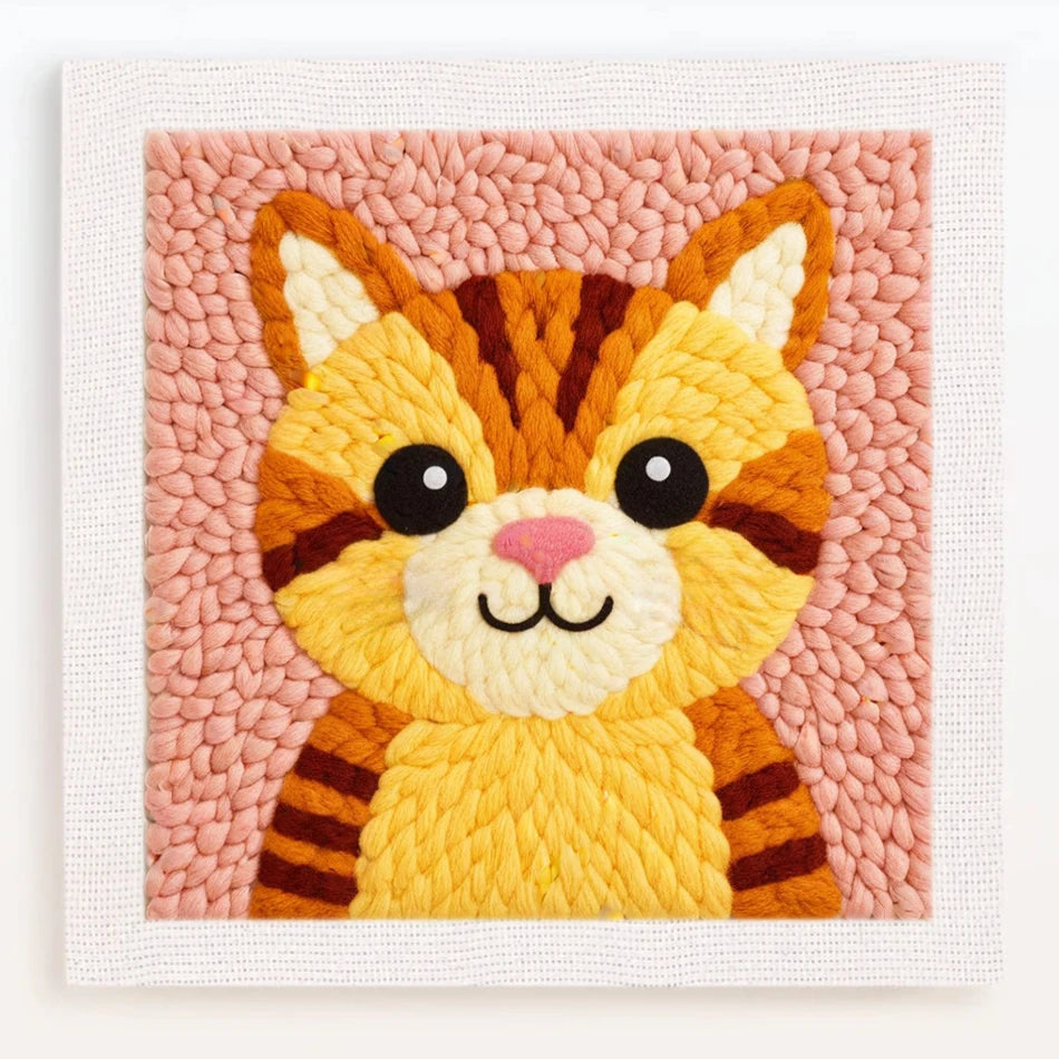 Bordado colorido de cara de tigre en hilos naranja, amarillo y marrón sobre tela rosa texturizada.