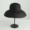 A black wide brim straw sun hat displayed on a stand.