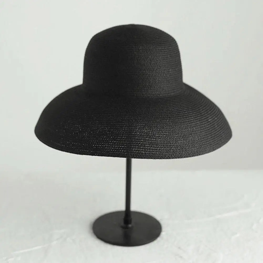 A black wide brim straw sun hat displayed on a stand.