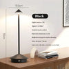 A black table lamp with a conical light source is shown on a wooden surface.