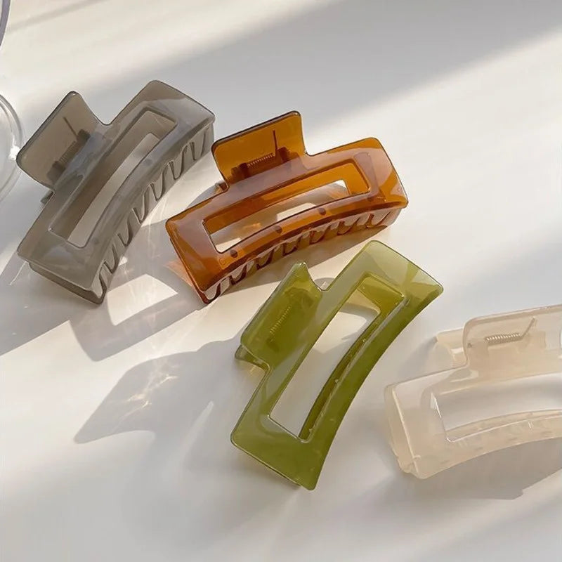 Three hair claw clips in matte finish colors gray amber and lime green are displayed on a white surface.