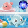 A light blue musical whale bath toy is shown spraying water in a blue bathtub.