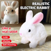 A realistic electric rabbit plush toy with pink ears and black eyes sitting on a textured surface.