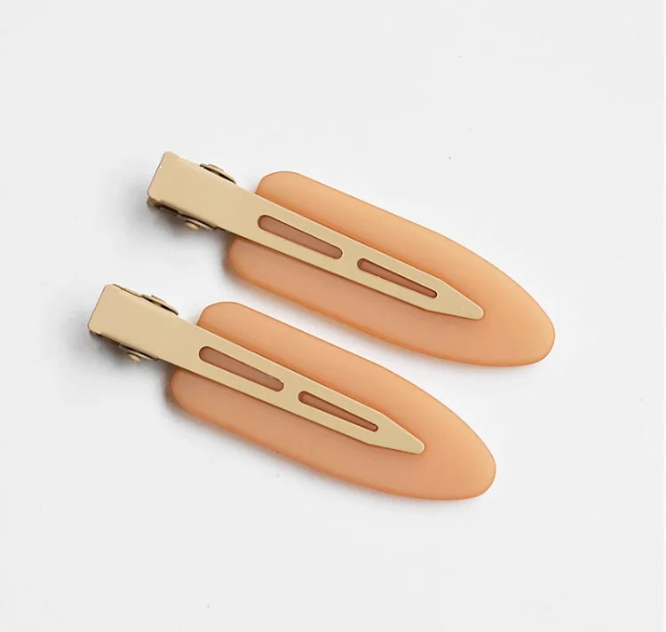 A set of two matte resin side hair clips in a nude or peach color, shown against a white background.