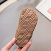 A close-up of a tan retro non-slip kids' moccasin shoe sole with wavy traction lines being held by a hand.
