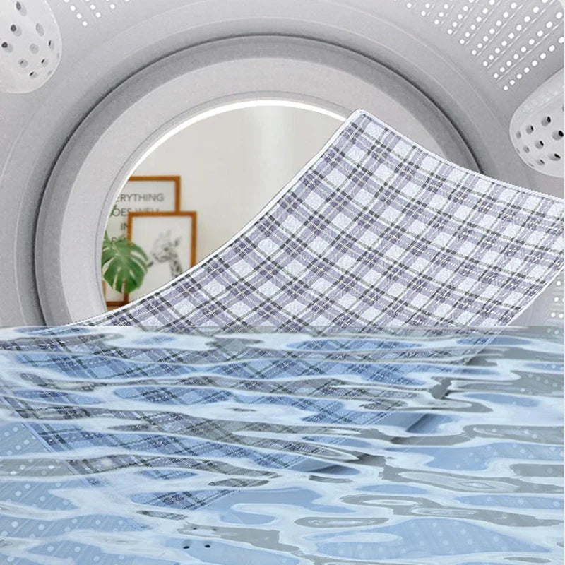 A close-up of a waterproof baby mattress protector with a plaid pattern and blue wavy design.