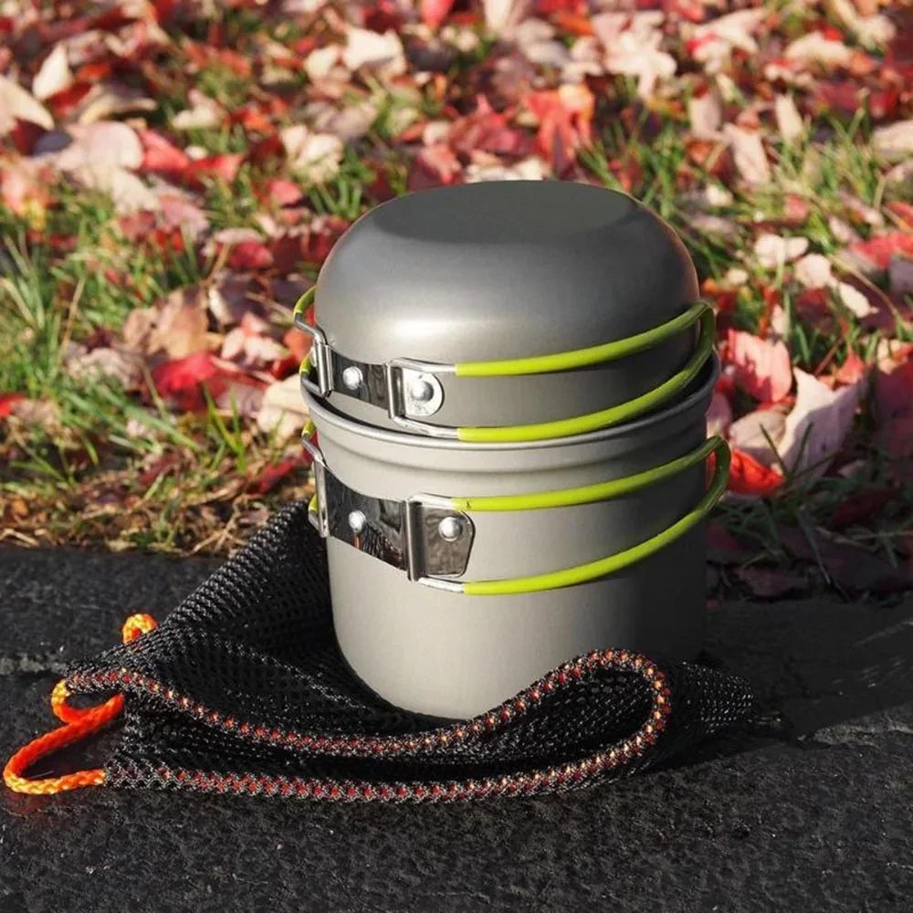 A gray ultralight camping cookware mess kit with yellow straps rests on a dark surface amidst autumn leaves.