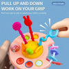 A hand is pulling a silicone pull string sensory toy with various colored strings and shapes on it.