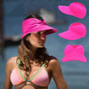 A woman models a bright pink UV-protective beach hat and matching bikini top against a blurred outdoor background.