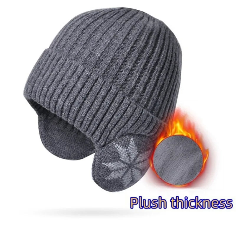 A gray knitted beanie with earflaps showing a plush thickness texture.