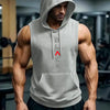 A muscular man wearing a gray hooded tank top and black athletic pants in a gym setting.
