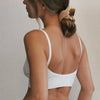 A woman shows the back of a white seamless U-back bralette top with light blonde hair in a bun.