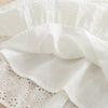 White cotton suspenders dress for a toddler girl with ruffled fabric and lace detailing