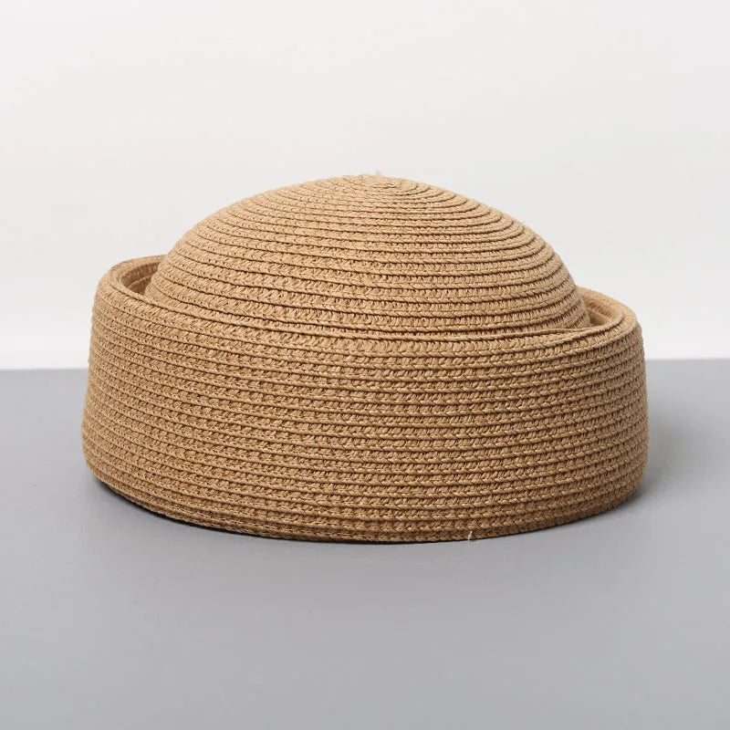 A woven straw pillbox sun hat in a natural tan color shown against a gray background.