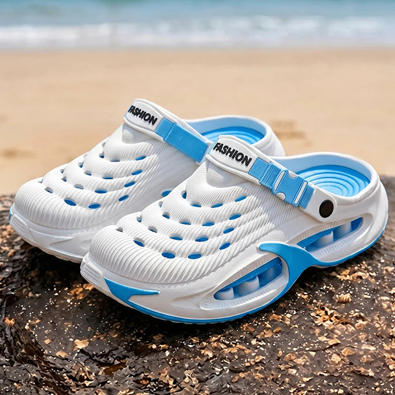 White and blue EVA slip-on sandals resting on a dark rock near the ocean.