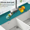 A silicone drain pad is installed at the bottom of a kitchen sink, featuring a faucet and fruit for cleaning.