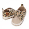 A pair of leopard print baby first walkers with soft rubber soles.