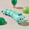 A line of pastel green wind-up crawling animal toys, including a worm and reptile, are displayed on a light surface.