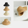 A set of three wide brim straw sun hats in varying shades of beige and black.