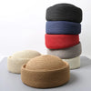 A stack of four straw pillbox sun hats in shades of black, blue, red, and beige.