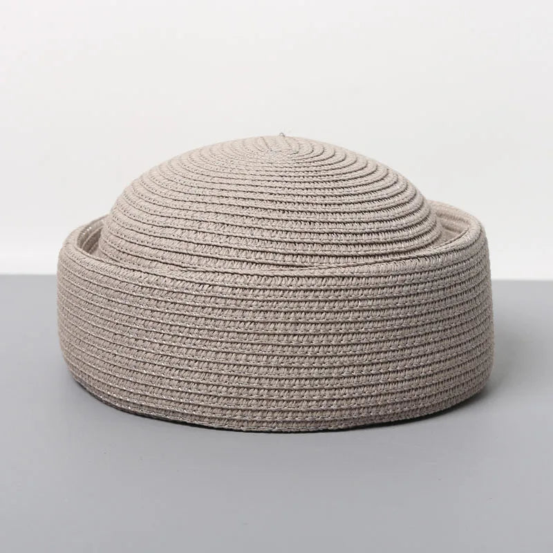 A beige straw pillbox sun hat with a wide brim, shown from above.
