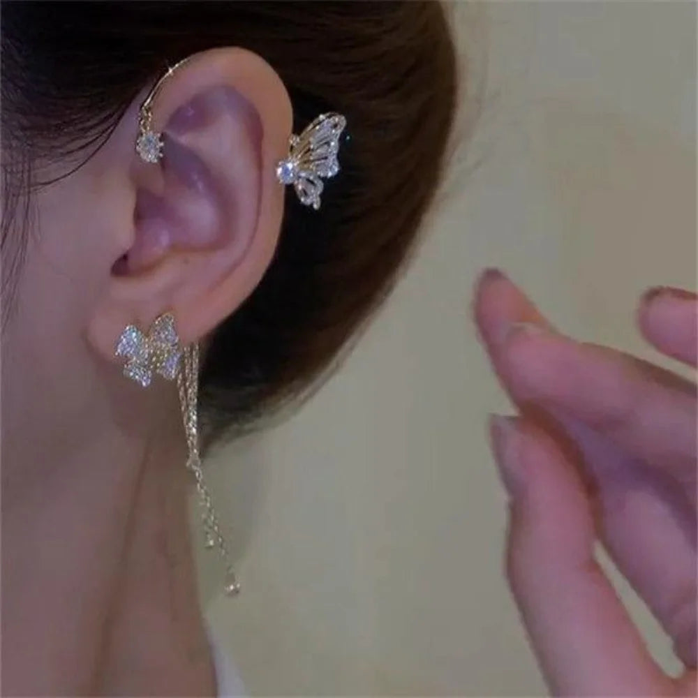 A close-up of a woman wearing butterfly zircon ear cuffs with gold tassels.