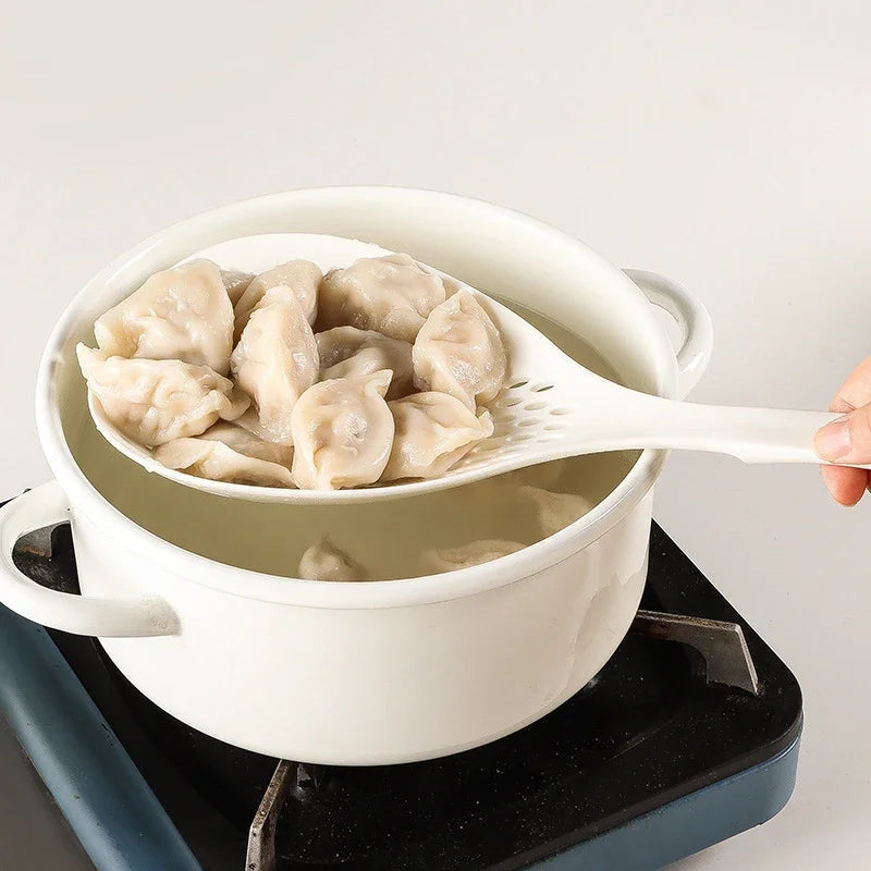 A white ceramic pot filled with light-colored dumplings served on a white spoon.