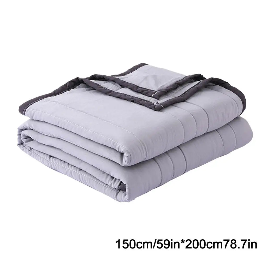 A stack of light gray breathable cooling throw blankets folded and stacked.