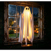 En hvid, lysende spøgelsesdekoration hænger i en vinduesramme og oplyser et udendørs Halloween-scene.