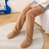 Ein Paar braune, fleece-gefütterte Overknee-Strümpfe mit offener Zehenpartie auf einem hellen Teppich.