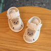 Pair of beige soft-sole sandals for a baby featuring bear-shaped accents