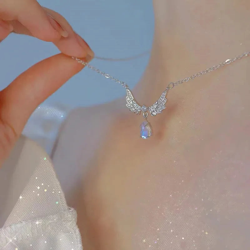 Silver crystal bow angel wings heart pendant necklace displayed on a neck.