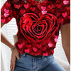 A woman models a red floral print t-shirt featuring a large rose design and small pink hearts, paired with blue jeans.