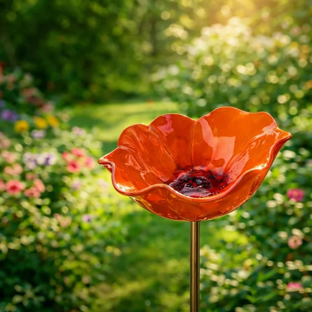 An orange handcrafted metal flower garden stake shaped like a bowl, set in a lush green garden.