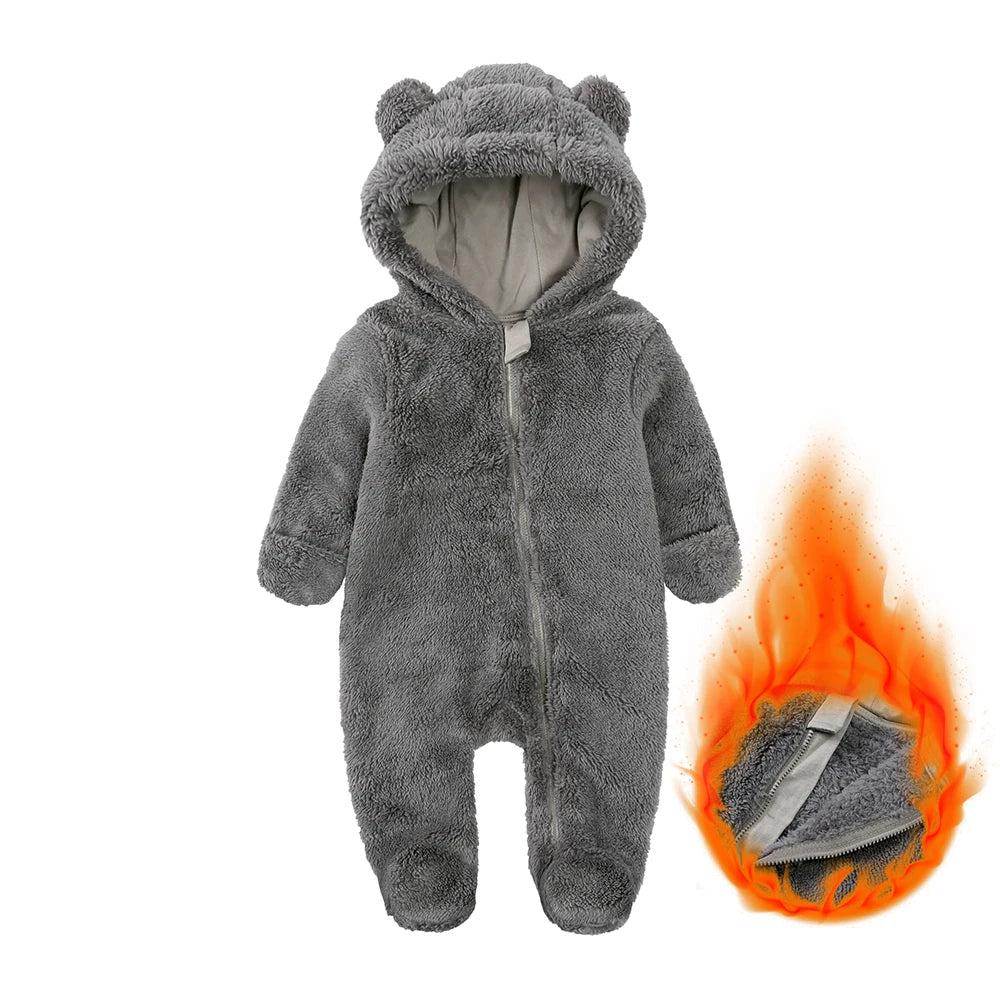 A gray fuzzy baby fleece hooded romper with a zipper is shown next to a small flame.