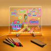 An LED glowing message board displays neon signals and a welcome message next to a set of seven colored pens.